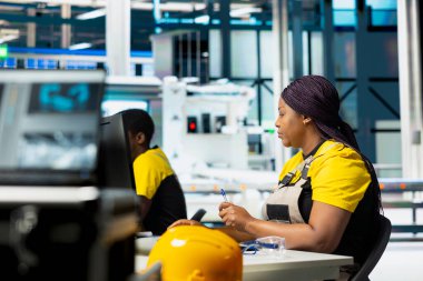 Mühendis modern fabrikada enerji optimizasyon yazılımı üzerinde çalışan PC 'deki güneş paneli sistemlerini ayarlıyor. Uzman, yüksek teknolojili otomatikleştirilmiş bir tesiste fotovoltaik operasyonları yönetiyor. Kamera A.