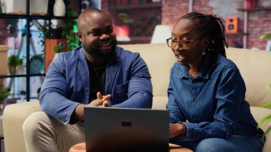 Siyah adam ve kadın rahat dairelerinde oturup dizüstü bilgisayarda dijital pazarlama stratejilerini tartışıyorlar. Birbirlerine uzak işlerinde ve serbest yolculuklarında destek oluyorlar. Kamera B.