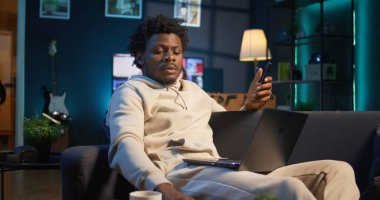 Black Freelancer araştırmasını evde makaleler ve veri odaklı kağıtlar okuyarak, telefon ve bilgisayar kullanarak yeni bir proje için bilgi toplayarak yapıyor. Adam birden fazla iş yapıyor ve dosyaları inceliyor. Kamera B.