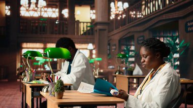 Tıp fakültesinde oksitölçer kullanan siyahi bir kız öğrenci ve uygulamayı okuyor, kütüphanede akademik veritabanı fotokopi kitaplarıyla çalışıyor. Bilgin tıbbi araştırmasını yapıyor. Kamera A.