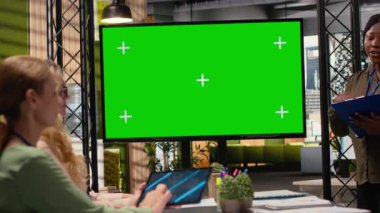 Hedefe yönelik iş kadınları, performans analizi ve planlama araçları için veri ve kararlılıkla güçlendirilmiş kağıtlarla bir model televizyon monitörü etrafında çalışırlar. İş ortamı. Kamera B.