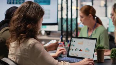 Masadaki grafikleri ve verileri analiz eden odaklanmış iş kadını, azim ve stratejik düşünce ile çalışıyor. Kurumsal hedefleri performans göstergeleriyle hizalamak. Kamera B.