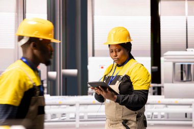 Kadın ngineer, dijital arayüz kullanılarak, robot silah ve montaj hatlarını optimize ederek Endüstri 4.0 fabrikasını izliyor. Profesyonel teknisyen üretim verimliliğini artırmak için otomatik sistemleri denetliyor.