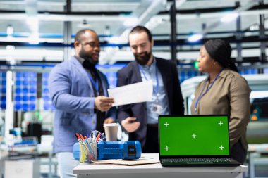 Profesyonel mühendislik grubu kroma anahtarının yanındaki güneş panellerini inceleyerek yeşil teknoloji ve çevre dostu yenilenebilir enerjide birlik gösteriyor. Üretim endüstrisinde operasyonel liderlik.