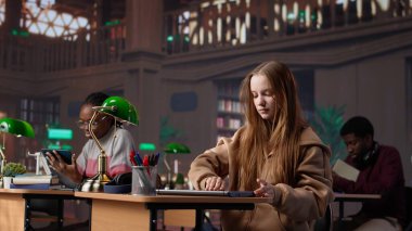 Üniversite kütüphanesine gelen odaklanmış bir kız, notlar yazmak için ders kitabını açıyor, kendi kendine öğrenim için belirlenmiş kampüs veritabanında kitlesel kitap veritabanı yardımıyla araştırma yapıyor. Kamera A.