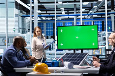 Müdür, güneş paneli materyalleri sunumunu modelleme monitörü kullanarak, fon sağlayarak yapıyor. İş kadını, yeşil ekran ekranı kullanılarak sunum sırasında sanayi tesisi varlıklarını hissedarlara gösteriyor