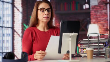 Evindeki bir web konferansı sırasında gülümseyen ve el sallayan odaklanmış bir kadın, dijital ve kablosuz bir yaşam tarzında sanal toplantı ve çevrimiçi iletişim sergiliyor. Kendinden geçmiş bir konferans konuşmacısı. Kamera A.