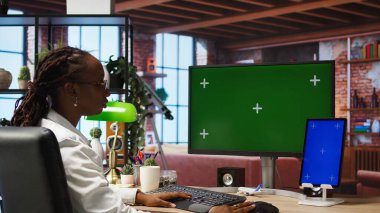 İş üzerinde çalışmak için yeşil ekran bilgisayar ve tablet kullanan uzaktan çalışan bir çalışan. Çevrimiçi iş yapmak için krom anahtar bilgisayar monitörü ve izole ekran aygıtı kullanan bir telemeci, kamera A