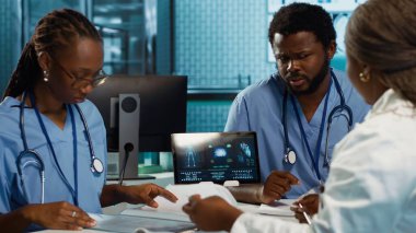 Uzman danışmanlık ve tedavi tavsiyeleri sağlamak için teşhis araçları ve verileri kullanan tıp uzmanları. Profesyonel bir sağlık ortamında bir grup asistan. Kamera A.