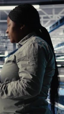 Dikey Veri Merkezi çalışanı altyapı süreçlerini izliyor, operasyonel ölçümleri gözden geçiriyor. Sunucu odası çalışanı denetleme sırasında yüksek teknolojili altyapı donanımı donanımı raporlarını inceliyor