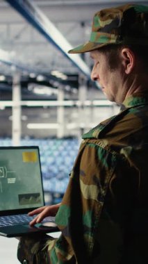 Veri merkezindeki dikey video askeri teknisyeni defter yazılım arayüzü kullanarak uydu koordinatlarını takip ediyor. Sunucu merkezindeki ordu birimi uydu görüntüleme yoluyla keşif verilerini analiz ediyor.