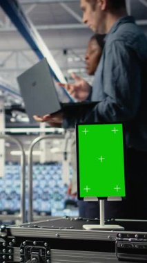 Dikey video Veri Merkezi çalışanları yapay zeka işlemlerini izole ekran tableti ile izleyip ölçümleri gözden geçiriyorlar. Mühendisler teftiş sırasında yapay zeka raporlarını incelemek için krom anahtar aygıt kullanırlar.