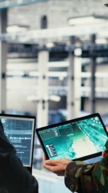 Veri merkezinde bulunan dikey video ordu komutanı ve yazılım geliştiricisi füze takibi için yapay zekayı radar sistemlerine entegre ediyor. Sunucu merkezinde hava hareketlerini analiz eden asker ve kadın programcı