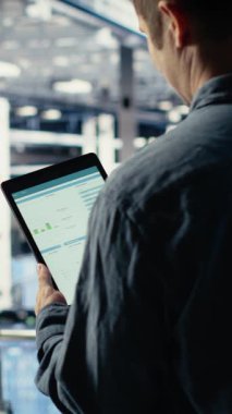 Dikey video sunucu odası bilişim uzmanı veri grafiklerini okumak ve ekipman sağlığını izlemek için tablet dokunmatik ekranını kullanıyor. Veri merkezinin çalıştığından emin olmak için aygıttaki analiz ölçüm grafiklerini incele