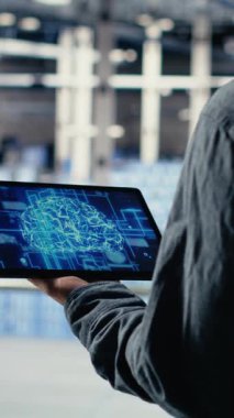 Dikey Veri Merkezi Sistem Yöneticisi, işlevsel ölçümleri gözden geçirip, derin öğrenme süreçlerini izler. Sunucu odası bilişim uzmanı ses kulaklığı takıyor, nöral ağların raporlarını gözden geçiriyor