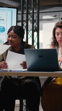 Brifing sırasında işbirliği yapan, veri ve raporları analiz eden ve bir büyüme zihniyetini benimseyen iş kadınlarının Dikey Video Grubu. Hedefe yönelik toplantı. Kamera A.