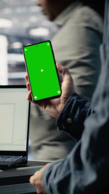 Güncellemelerin kurulumunu beklerken model telefon kullanan dikey video sunucu odası yazılım geliştiricisi. Veri merkezi mühendisi derlemeyi bitirmek için yeşil ekran akıllı telefonu kullanıyor