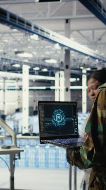 Yüksek teknoloji sunucu merkezindeki dikey video ordu programcısı keşif bilgilerini incelemek için yapay zeka uygulamasını kullanıyor. Veri Merkezi bilişim uzmanı askeri üniforma giyiyor. Not defterinde yapay zeka kullanıyor.