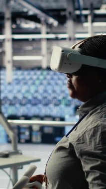 Dikey video veri merkezi bilişim uzmanı sanal gerçeklik kullanarak yapay zeka yapılandırmalarını araştırır ve optimal fonksiyon için ayarlamalar yapar. Sunucu merkezi mühendisi VR kullanarak yapay zeka hatalarını kontrol ediyor