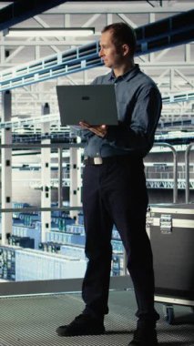 Endüstriyel platformdaki dikey video veri merkezi yönetimi Al 'ın kontrol panelini dizüstü bilgisayarla kontrol ediyor. Sunucu çiftliğindeki adam güvenilir performans sağlamak için yapay zeka araçlarını not defterinde test ediyor. Kamera A