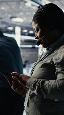 Vertical Video Veri Merkezi Yöneticisi, müşterilerin web sitesi sunucu sorunlarını çözmelerine yardımcı olmak için tablet üzerinde yapay zeka kullanır. Sunucu çiftliğindeki Afrikalı Amerikalı kadın kullanıcıların çevrimiçi hizmetleri sürdürmelerine yardımcı oluyor