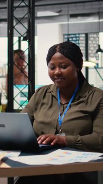 Vertical Video Business danışmanı finansal verileri analiz ediyor ve gösterişli bir ofiste raporlar yazıyor, finansal durumu grafikler ve içgörülerle değerlendirerek şirketin faaliyetini geliştiriyor.