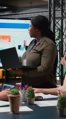 Dikey Video Yöneticisi, mali durumu TV ekranında sunuyor. İş arkadaşlarıyla geliştirme ve problem çözme konularını tartışıyor. Tüm bayan takımlar brifing oturumunda.