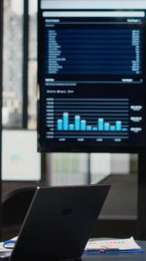 Bir dizüstü bilgisayar ve performans raporlarıyla donatılmış dikey video sessiz şirket alanı, veri odaklı karar verme, tahmin ve stratejik analizler için hazır modern bir iş ofisini temsil etmektedir..