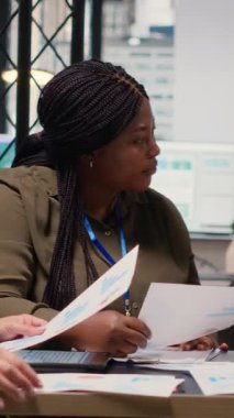 Dikey video çeşitliliğindeki kadınların yeni strateji için biraraya gelmesi ve bilgi alışverişinde bulunması, ofisteki belgelerin grafiklerini gözden geçirmesi. Hedefe yönelik güçlendirilmiş ortam, kurumsal feminizm. Kamera.