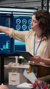 Modern ofisteki verimliliği sembolize eden bir toplantıda, şirket vizyonunu ve hedeflerini iyileştirmek için analitikleri gözden geçiren dikey Video İş Kadınları. Profesyonellik ve kurumsal feminizm