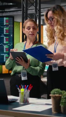 Ofiste stratejik işbirliğini temsil eden dikey Video Hedefleri odaklı iş kadınları, tablet ve veri raporlarını kullanarak şirketler arasında güçlü hedefler belirlemek ve başarı sağlamak amacıyla