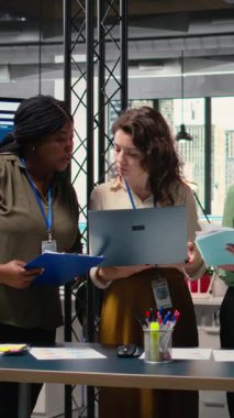 Dikey video çeşitliliğindeki kadınlar proje gelişimini tartışıyor ve kurumsal feminizm ve stratejik hizalama yoluyla elde edilen başarıyı temsil eden canlı bir modern ofiste göstergeler sunuyorlar.