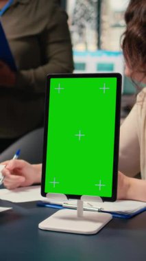 Modern ofis toplantısında krom anahtar ekranı kullanan, dijital planlamayı destekleyen ve performans veri raporlarını inceleyen dikey video iş ortakları grubu. Stratejik düşünce ve vizyon. Kamera A.