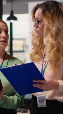 Ofiste stratejik işbirliğini temsil eden dikey Video Hedefleri odaklı iş kadınları, tablet ve veri raporlarını kullanarak şirketler arasında güçlü hedefler belirlemek ve başarı sağlamak amacıyla