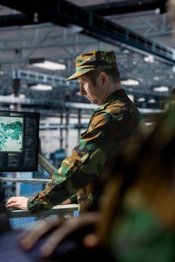 Sunucu merkezindeki asker veri işlemleri çalışma istasyonu monitöründeki raporları kontrol ediyor. Operasyonel veri merkezinde görüntüleme kullanarak üniforma izleme sistemi takan ordu bilgi uzmanı