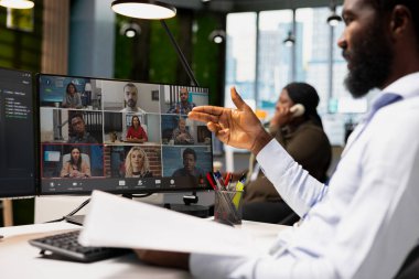 Ekip liderinin video görüşmesinde evrakları gözden geçirmesini uzaktan çalışan personelle konuşmasını sağla. Çevrimiçi telekonferans sırasında ofis masasında çalışan yönetici dosyaları okuyor.