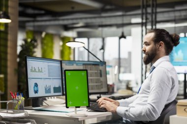 Bilgisayardaki bilgi grafikleri ve veri analizleriyle birlikte görevi tamamlayan, bilgisayarın yanındaki tabletin yanındaki KPI metriklerini analiz eden yönetici yardımcısı. İş adamı öngörüleri görüyor.