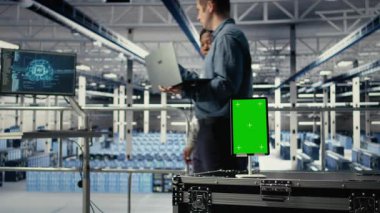 Derin öğrenme sistemlerini optimize eden ve görevlerle ilgilenen yöneticilerin önündeki sunucu odasında yeşil ekran tableti. Yapay zeka model parametrelerini ayarlayan veri merkezi çalışanları tarafından kullanılan model cihazı, kamera A