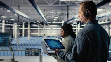 Veri merkezi sistem yöneticisi derin öğrenme süreçlerini izler, operasyonel ölçümleri gözden geçirir. Sunucu odası bilişim uzmanı ses kulaklığı takıyor, sinirsel ağ raporlarını gözden geçiriyor, kamera A