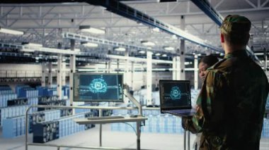 Yüksek teknoloji sunucu merkezindeki ordu programcısı keşif bilgilerini incelemek için yapay zeka uygulamasını kullanıyor. Askeri üniforma giyen veri merkezi bilişim uzmanı görevi planlamak için yapay zeka kullanıyor. Kamera A.