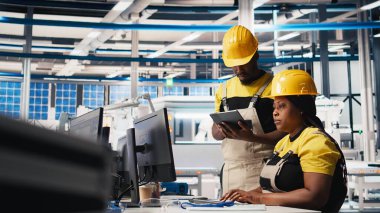 Fabrikadaki güneş paneli üretimi için bilgisayar, sorun çözme ve teknik sorunları çözme konusunda kalite kontrolü yapan Afrikalı Amerikalı bir ekip. İş arkadaşları sistemi inceliyor. Kamera B.