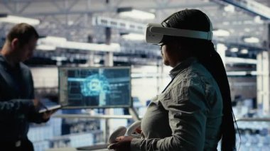 Sunucu odasında VR gözlük takan yazılım geliştirici derin öğrenme sistemlerini optimize ederek görevleri yerine getiriyor. Veri merkezindeki Afrikalı Amerikalı kadın yapay zeka parametrelerini sanal gerçeklik, kamera B kullanarak ayarlıyor.