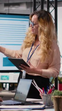 Dikey Video Genel Müdürü, iş verimliliğini incelemek üzere ekrana işaret ederek veri odaklı raporları sunmak üzere ekibiyle bir brifing toplantısına ev sahipliği yapıyor. Profesyoneller stratejiyi somutlaştırır