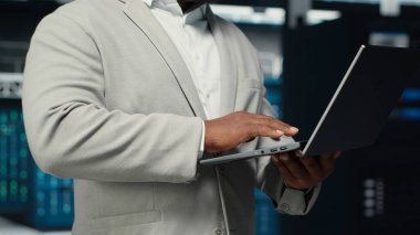 Veri merkezinde yürüyen bir mühendisin sistem istikrarı için teçhizatı kontrol etmesi. IT uzmanı sunucu çiftliğini denetliyor, ana bilgisayarları yapılandırıyor, performansı optimize ediyor