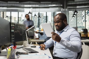 Aksesuar firması stajyeri, ekrandaki şamdan çizelgelerini ve fiyat grafiklerini anlamak için karışık notlar okuyor. Ticaret stratejilerinin analizini anlamakta zorlanan eski ticaret firması stajyeri