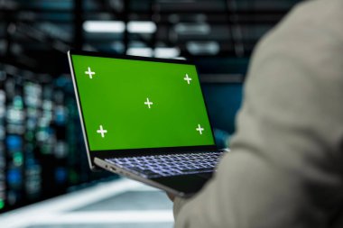 Sunucu tarım yazılım geliştiricisini veri depolama ekipmanlarını tamir etmek için dizüstü bilgisayar kullanarak kapat. Bilişim uzmanı, hesaplama işlemleri yapan yükleri temizlemek için yeşil ekran defteri kullanıyor