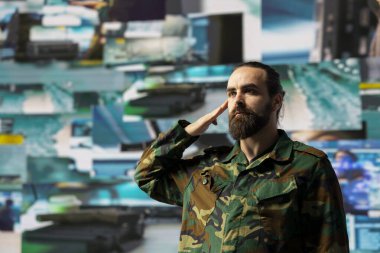 Kıdemli asker, savaş alanı detaylarıyla savaş planlama taktikleri üzerinde çalışan bir kontrol merkezinde uydu verilerini gözden geçirdikten sonra selam veriyor. Ulusal güvenlik için yüksek teknoloji ordu ortamı.