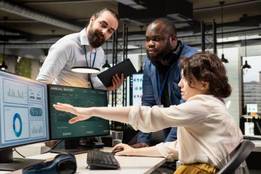 Strateji planlaması yapan ve rapor yazan çok ırklı bir grup insan, ticari veri içgörülerini hedeflerle aynı hizaya getirmek için kullanıyor. Ofisteki bilgisayardaki raporlar inceleniyor.