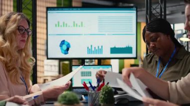 Bilgi raporlarıyla birlikte strateji oluşturan, şirket sinerjisi hedeflerine ulaşmak için kağıtlardaki finans bilgilerini analiz eden güçlü bir kadın grubu. Paylaşılan anlayış ve liderlik. Kamera A.