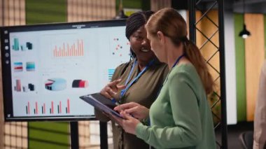 Dinamik bir çalışma ortamında finans raporları ve analizleri gözden geçirmek için birleşen çok ırklı iş kadınları, performans göstergelerini vizyon stratejisi ve güçlü takım sinerjisi ile harmanlıyor. Kamera B.